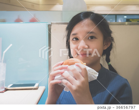 Asian girl in eating a hamburger in the restaurant Asian girl in eating a hamburger in the restaurant 36656797