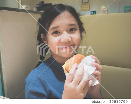 Asian girl in eating a hamburger in the restaurant Asian girl in eating a hamburger in the restaurant 36656799