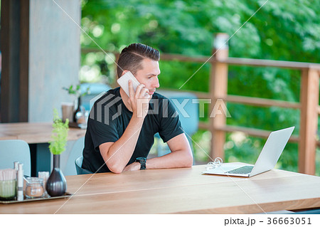 Young man talking by smartphone in outdoor cafe 36663051