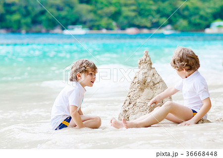 Two kid boys building sand castle on tropical 36668448