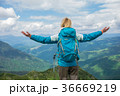 Woman with arms raised on top of mountain looking 36669219