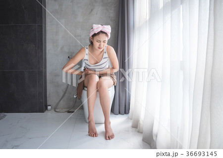Beautiful woman with stomachache sitting in toilet 36693145