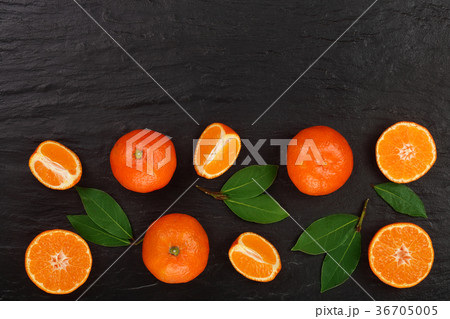 orange or tangerine with leaves on black stone 36705005