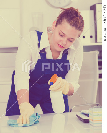 Happy housekeeper is cleaning dust from the desk Happy housekeeper is cleaning dust from the desk 36717945