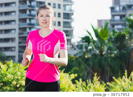 Smiling woman in pink T-shirt is jogging Smiling woman in pink T-shirt is jogging 36717952