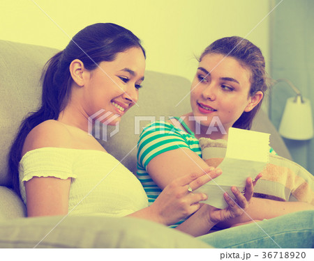 Teenagers girls reading letter on couch Teenagers girls reading letter on couch 36718920