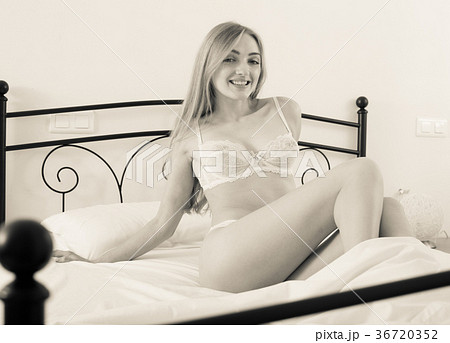 Young Woman Wearing Revealing Underwear Lounging In Bedroom Stock