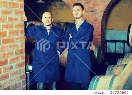 two men in uniforms standing in cellar with wine woods two men in uniforms standing in cellar with wine woods 36720605