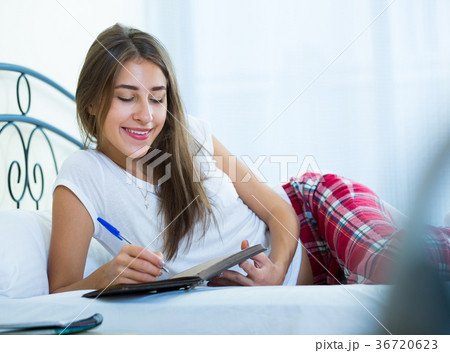 Smiling girl making shopping list in bedroom Smiling girl making shopping list in bedroom 36720623