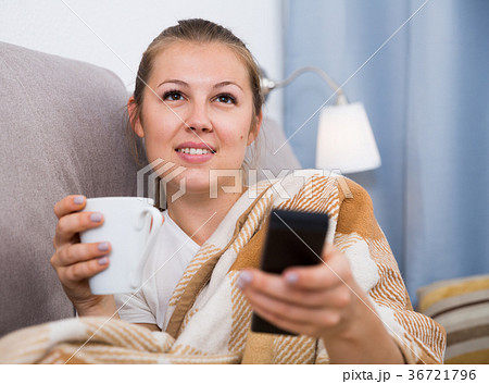 Girl is resting with tea in plaide and watching TV Girl is resting with tea in plaide and watching TV 36721796