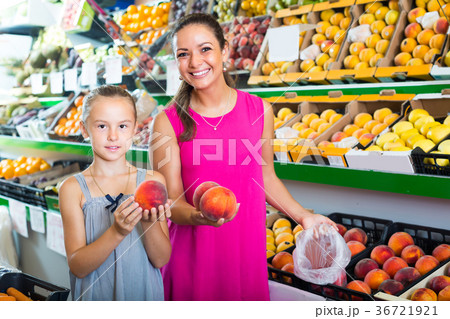 mother with girl taking peaches on market . 36721921