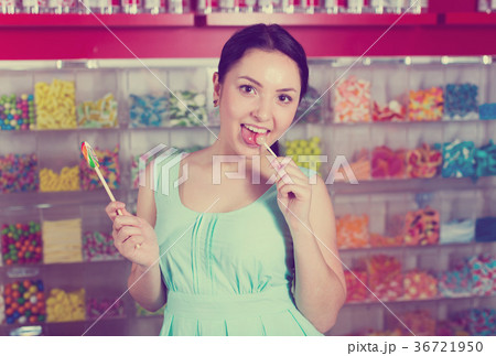 Smiling girl sucking lollypop in store 36721950