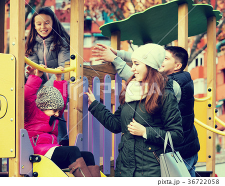 parents with two daughters playing at children's slide 36722058