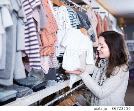 girl deciding on warm romper suit for baby in children’s clothes store girl deciding on warm romper suit for baby in children’s clothes store 36722250