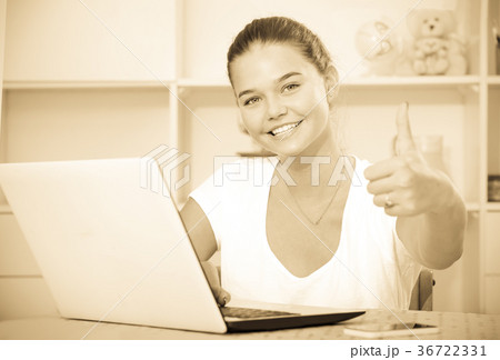 girl school pupil sitting with laptop and showing thumbs up 36722331