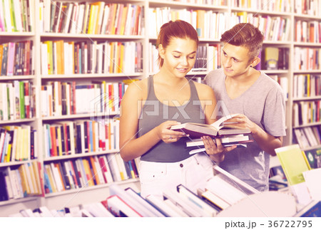 Two smiling teenagers reading book together 36722795