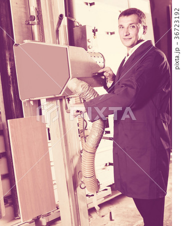 portrait of man in uniform working on large automatic saw machinery indoors 36723192