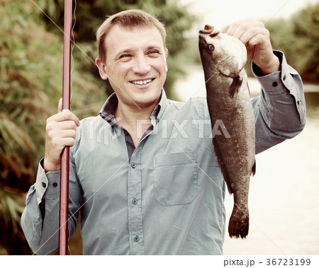 Fisherman holding catch freshwater fish in hands on lake Fisherman holding catch freshwater fish in hands on lake 36723199