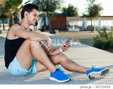 Man using smartphone during break in workout outdoors 36723830