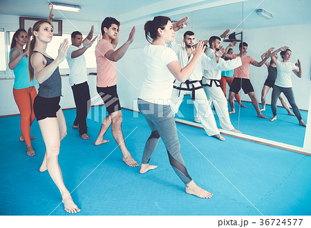 adults attempting to master new moves during karate class 36724577