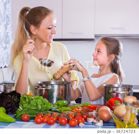 Woman and girl cooking veggies. Woman and girl cooking veggies. 36724723