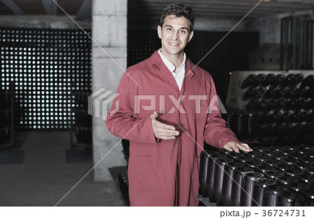 Man winery working in aging section with bottle racks in cellar 36724731