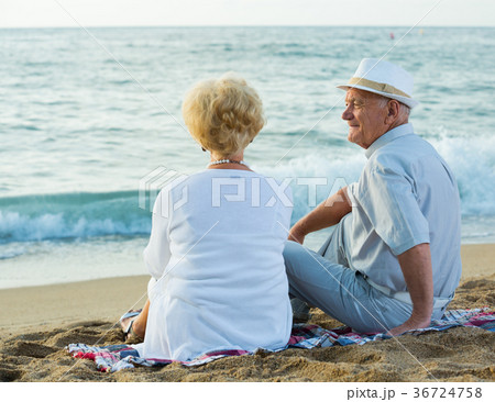 Mature man and woman sitting back on towel Mature man and woman sitting back on towel 36724758