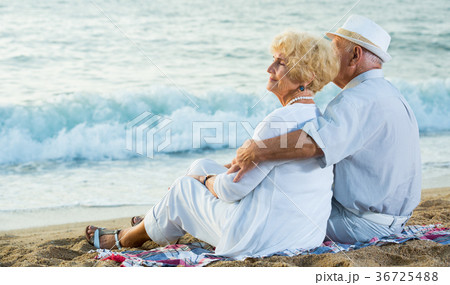 man and woman sitting on the sea shore 36725488