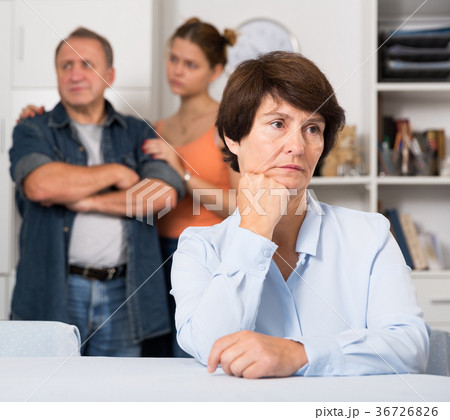 Man and his daughter are sympathying their sad mother who is sitting at the table 36726826