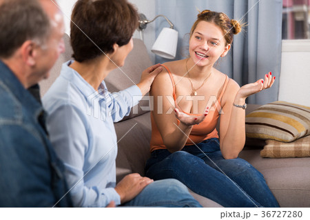 Marrieds with their adult daughter are talking together on sofa 36727280