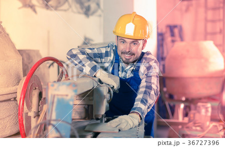Adult male worker cutting tile with disk saw 36727396