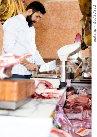 Male shop assistant carving meat Male shop assistant carving meat 36727522