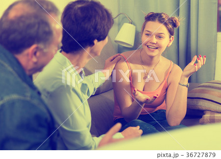 Marrieds with their adult daughter are talking together on sofa 36727879