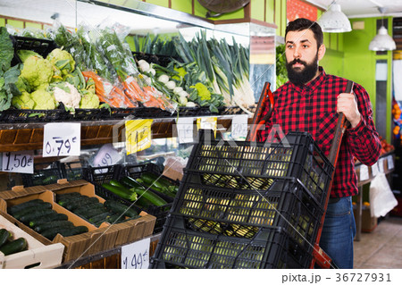 Young male seller moving fresh vegetables Young male seller moving fresh vegetables 36727931