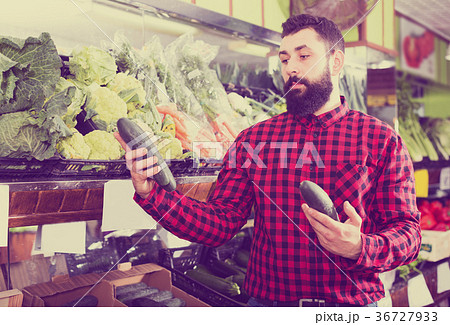 Shop assistant demonstrating zucchinis 36727933