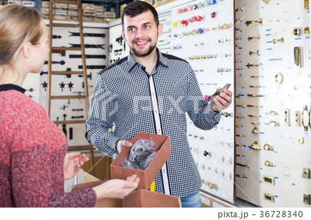 professional male seller assisting woman in choosing door handles in shop professional male seller assisting woman in choosing door handles in shop 36728340