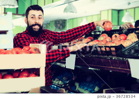 Male seller offering pomegranates in shop Male seller offering pomegranates in shop 36728534
