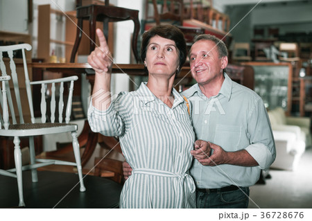 Man with wife are choosing old antique chair in shop Man with wife are choosing old antique chair in shop 36728676