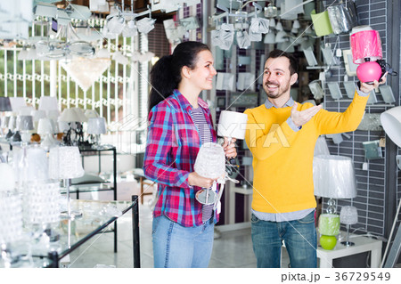 Family of two in shop of home appliances are choosing night lamp 36729549