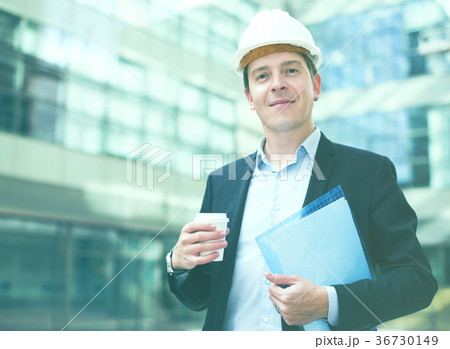 Smiling male architect in helmet with coffee 36730149