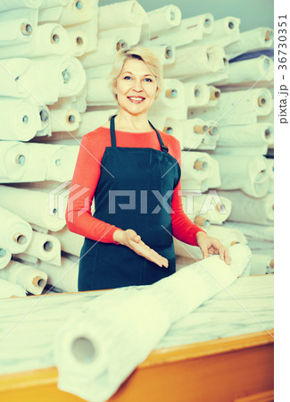 Aged seller is demonstrating fabrics 36730351