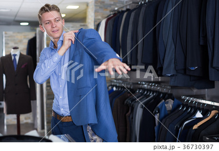 Adult male in suit trying jacket in the store Adult male in suit trying jacket in the store 36730397