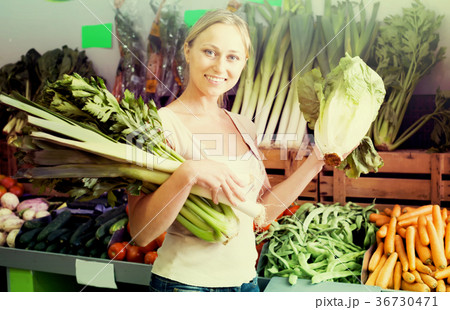 cheerful young female customer holding fresh celery and leek 36730471
