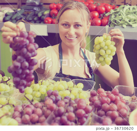 Seller holding bunch of grapes 36730620