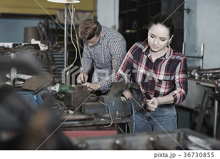 Girl worker is standing near vise equipment in workshop. 36730855