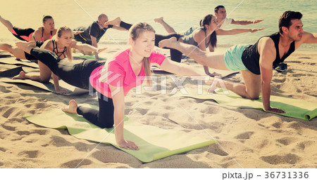 Sporty people practicing yoga on beach Sporty people practicing yoga on beach 36731336