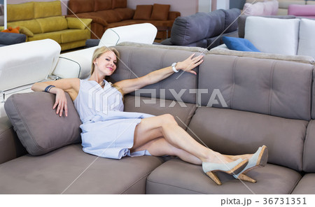 joyous female is testing sofa in furniture store 36731351