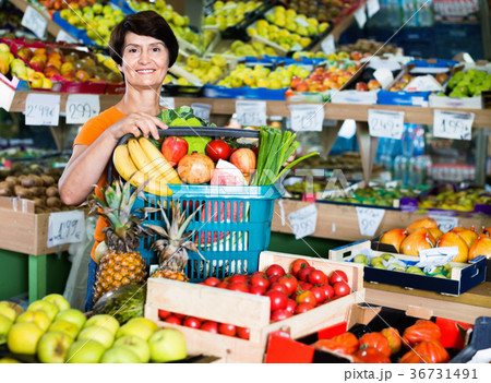Smiling female is standing with basket with vegetables and fruits Smiling female is standing with basket with vegetables and fruits 36731491