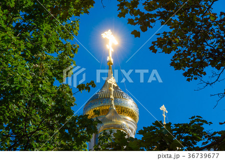 Cross with sunlight flare surrounded by foliage 36739677