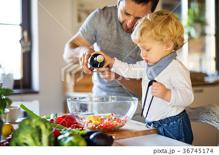 Young father with a toddler boy cooking. Young father with a toddler boy cooking. 36745174